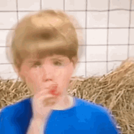a boy in a blue shirt is eating a lollipop .