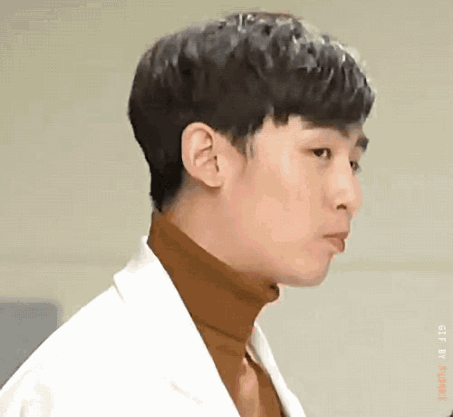 a close up of a man wearing a white coat and a brown turtleneck sweater