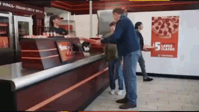 a man is getting a pizza from a counter in a pizza restaurant .