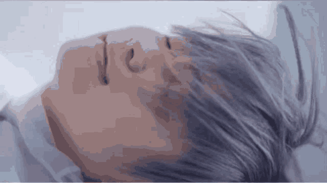 a close up of a person 's face with their eyes closed and their hair blowing in the wind .