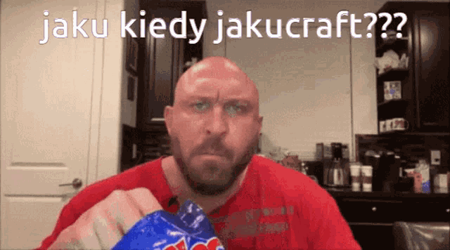 a bald man with a beard is eating a bag of m & m 's chips