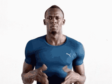a man in a blue shirt is standing with his arms outstretched .