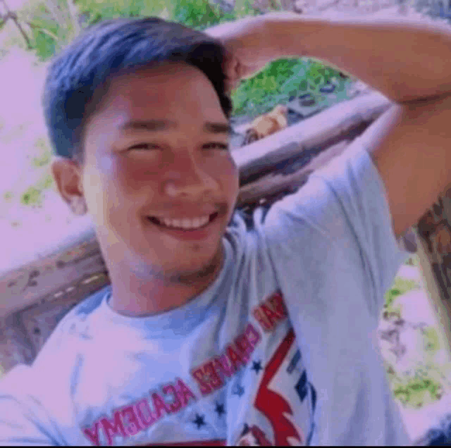 a man in a blue t-shirt is smiling and taking a selfie .