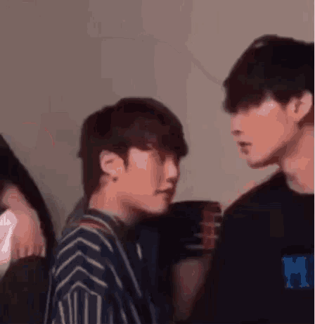 two young men are standing next to each other in a room and looking at each other .