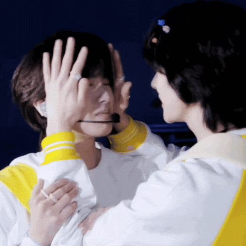 a man with a microphone covering his face while another man looks on