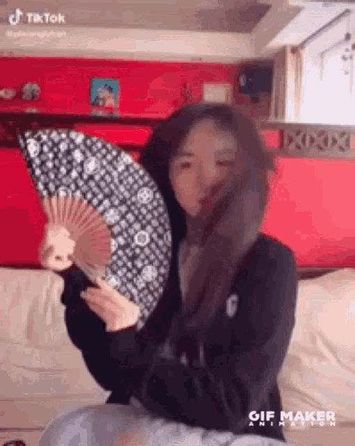 a woman is sitting on a couch holding a fan in her hands .