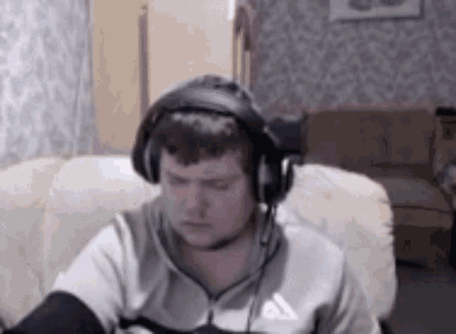 a man wearing headphones and a microphone is sitting on a couch .