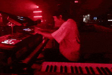 a man is playing a keyboard in a red light