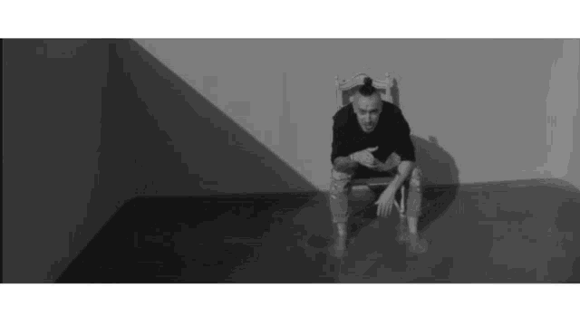 a man with a ponytail is sitting in a chair in a room .