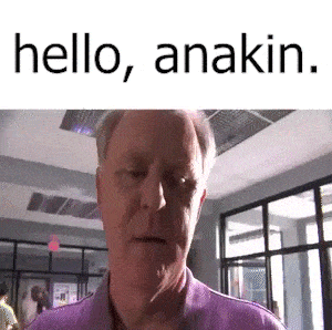 a man in a purple shirt is standing in front of a window and says `` hello , anakin '' .