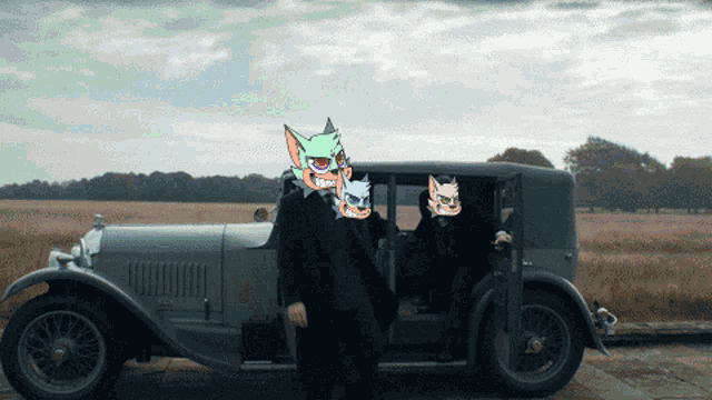 a man in a suit stands in front of an old car with cartoon faces on it