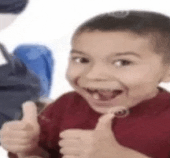 a young boy is smiling and giving a thumbs up sign .