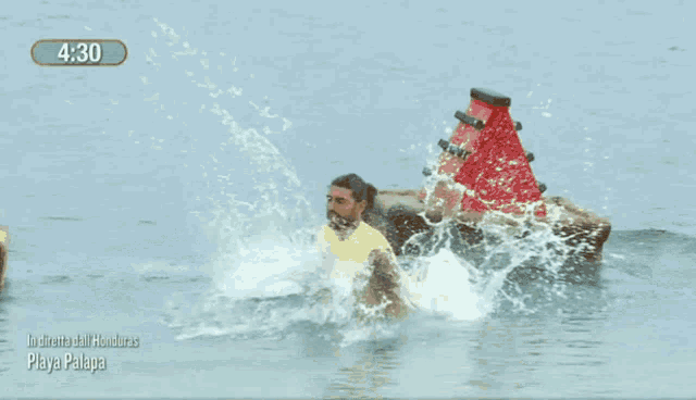 a man in a yellow shirt is standing in the water near a buoy
