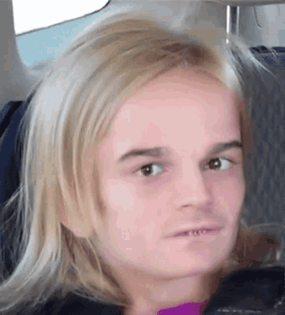 a close up of a person 's face with long blonde hair making a funny face