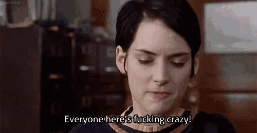 a woman with short black hair is sitting in a room and says `` everyone here 's fucking crazy '' .