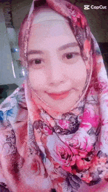 a woman wearing a hijab and a scarf is smiling for the camera .