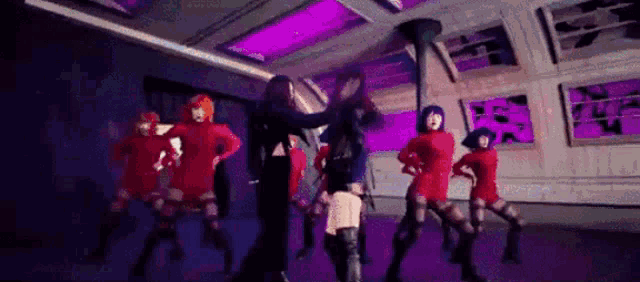 a group of dancers are dancing in a dark room .