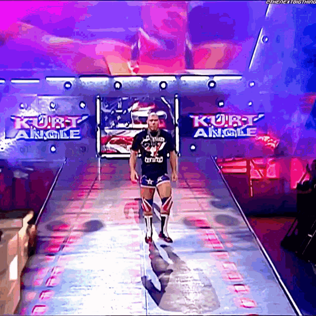 a man is walking down a ramp with kurt angle written on the wall behind him