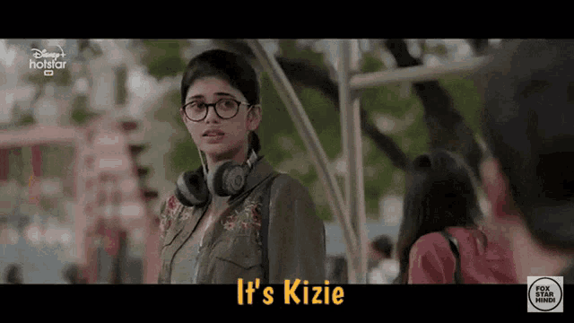 a girl wearing headphones says it 's kizie in front of a man