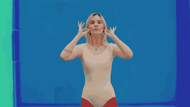 a woman in a white leotard is making a funny face with her hands