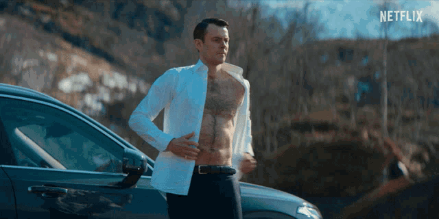 a shirtless man is standing next to a car with netflix written on the bottom right