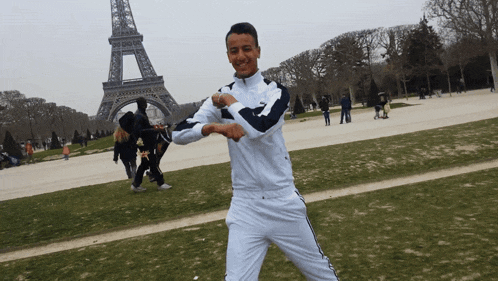 a man standing in front of the eiffel tower with his arms outstretched