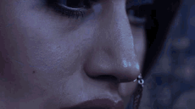 a close up of a woman 's face with blue eyes and a nose ring