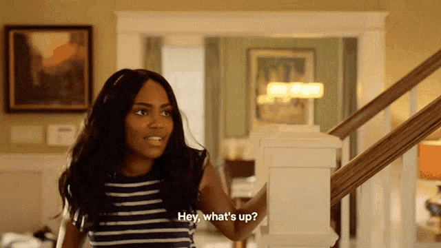 a woman is standing on a set of stairs and says hey what 's up .