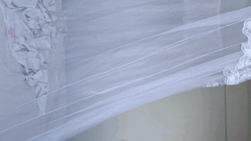 a doll in a colorful dress is laying on a bed under a canopy