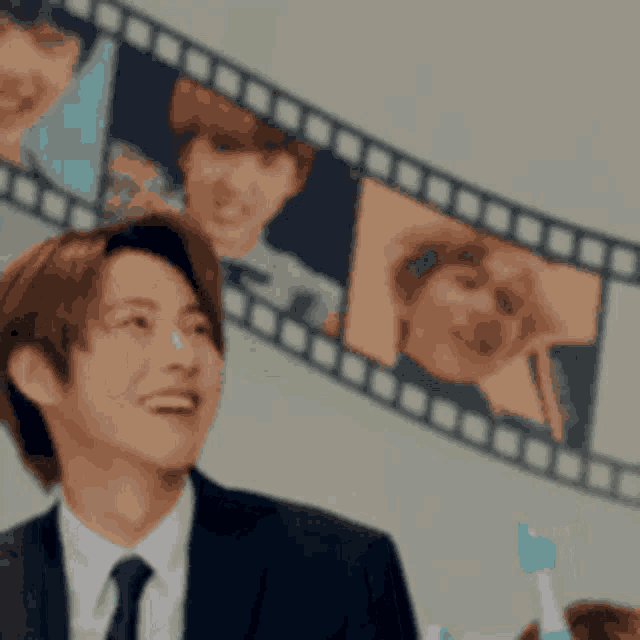 a man in a suit and tie is smiling while holding a toothbrush in front of a film strip .