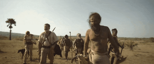 a group of men are walking in the desert with a dog