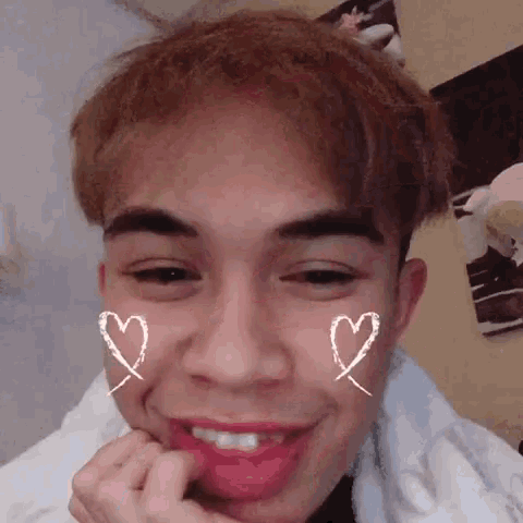 a close up of a young man with hearts drawn on his face and mouth .