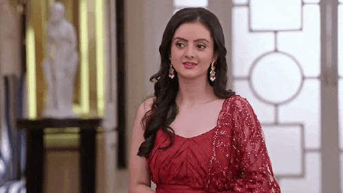 a woman in a red dress is standing in a room and smiling .