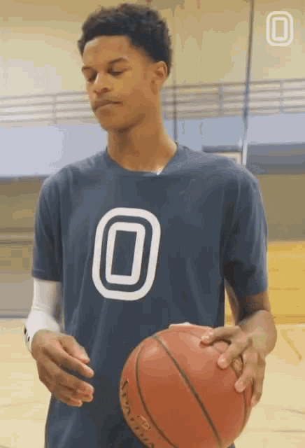 a young man in a blue shirt with the number 0 on it holds a basketball
