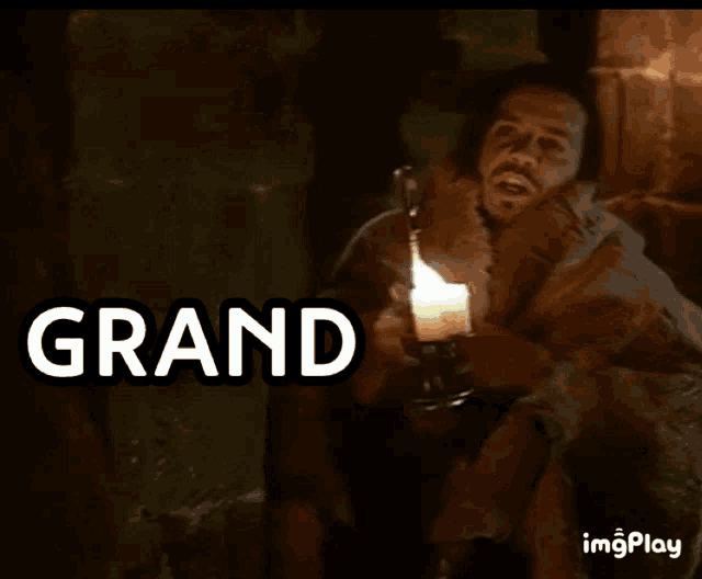 a man is holding a lit candle with the words grand cornichon behind him