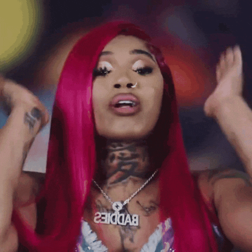 a woman with red hair is wearing a necklace with the word baddie on it