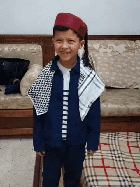 a young boy wearing a blue jacket and a red hat is smiling