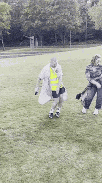 a man in a yellow vest is standing in a field
