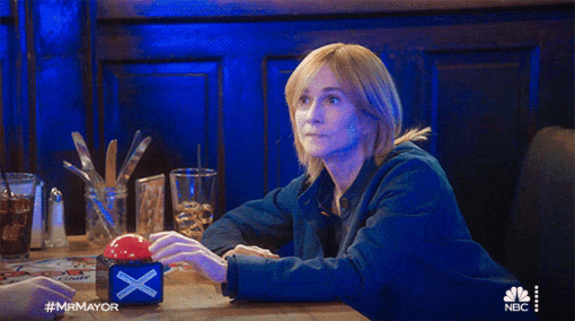 a woman is sleeping at a table with a nbc logo on the bottom