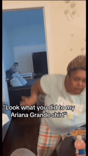 a woman says " look what you did to my ariana grande shirt " while standing in a room