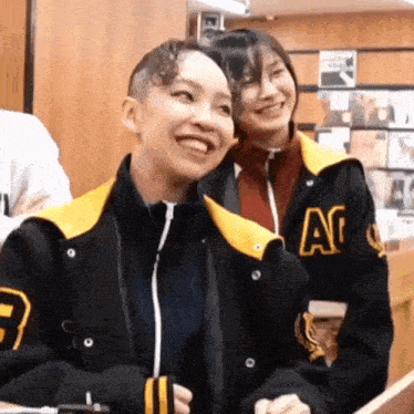 two women are standing next to each other and smiling in a store .