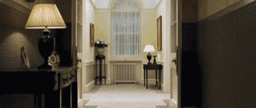 a hallway with two lamps and a vase of flowers on a table