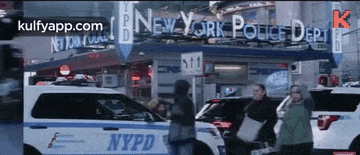 a group of people are walking in front of a new york police department
