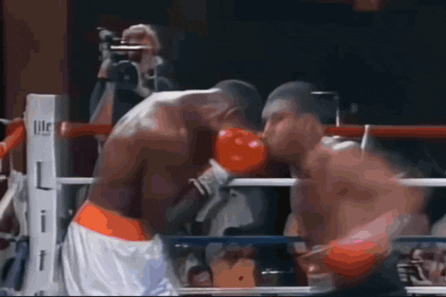 two boxers are fighting in a ring with a cameraman behind them