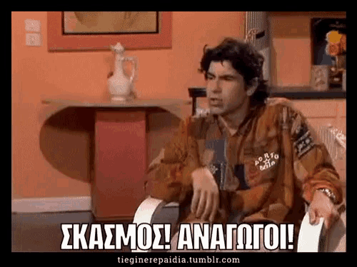 a man sitting in a chair with the words skasmos anagoi written on the screen