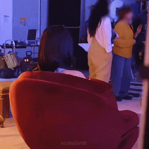 a woman sitting in a red chair with the name nojinsfaerie on the bottom right