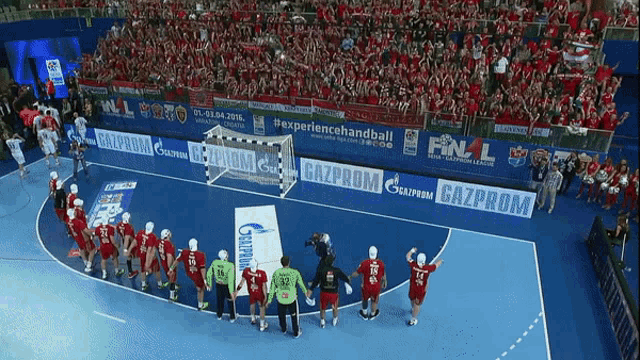 a group of handball players standing on a court in front of an advertisement for gazprom
