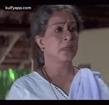 a woman with gray hair is wearing a white shirt and earrings and making a funny face .