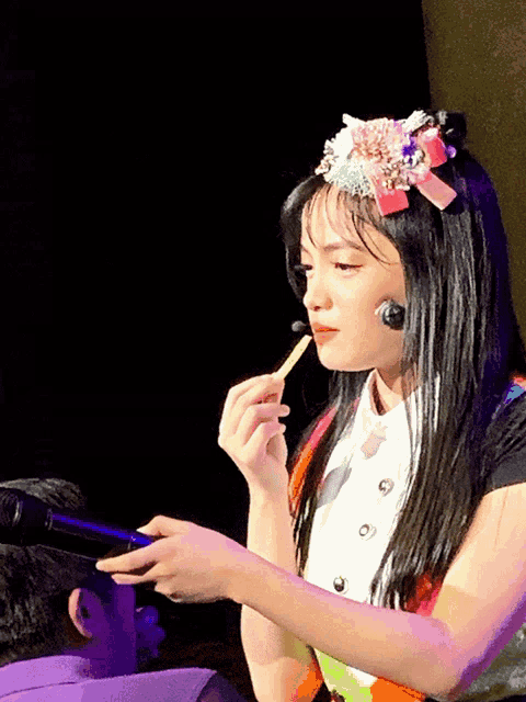 a girl wearing a headband with flowers on it is eating french fries