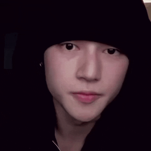 a close up of a person 's face wearing a black hat and earrings .